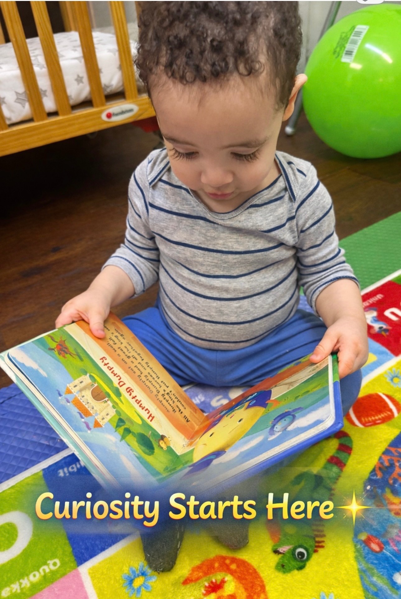 Child sitting on a colorful mat exploring a picture book