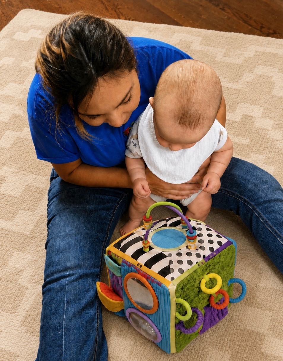 Caregiver nurturing an infant during sensory play with a colorful activity cube