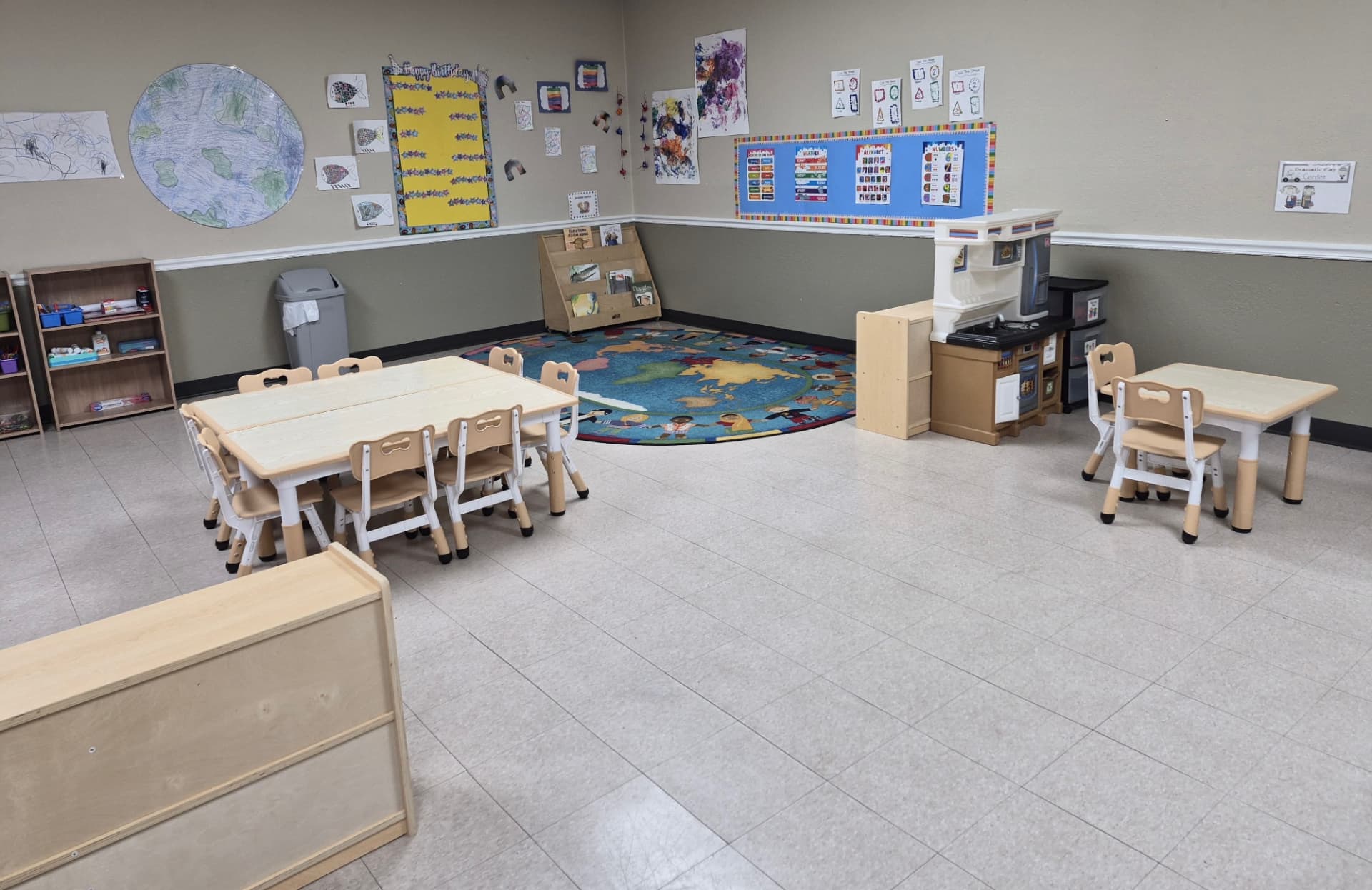 Pre-K room with children's artwork, world map rug and reading center