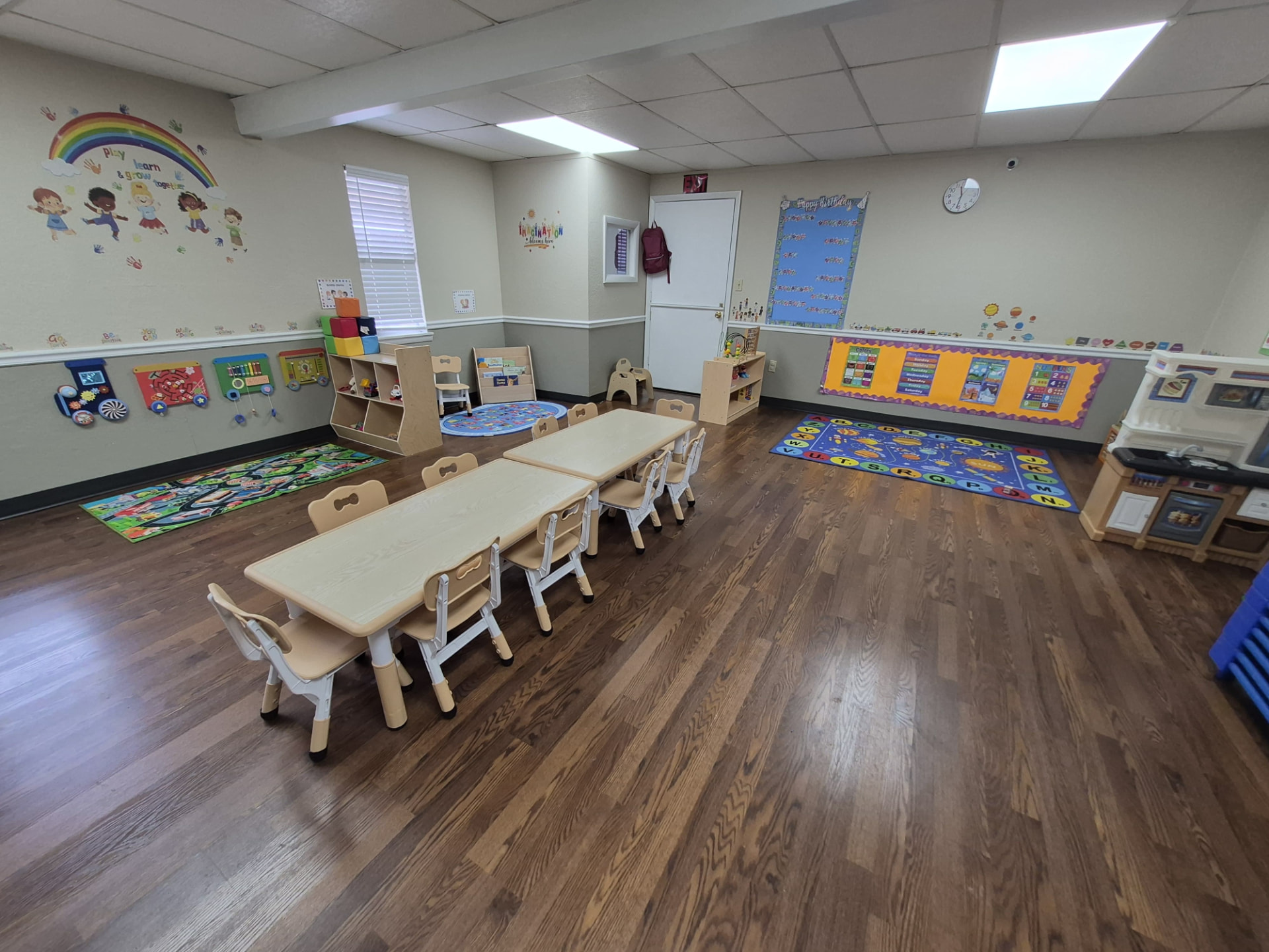 Bright classroom with reading nook, circle time board and play kitchen